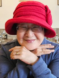 Claire Martin, lady wearing red hat with hands crossed under her chin